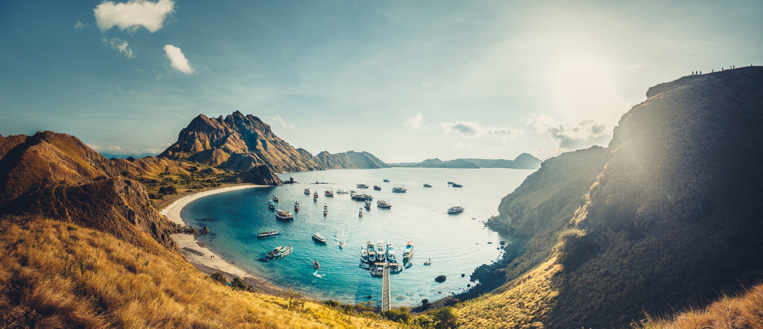 Mountains, bay, sun rays. Aerial shot. Padar. Wonderful panoramic overview the cute bay with the sand beaches surrounded by the mountains. Landscape of Padar island. Komodo National Park. Indonesia.